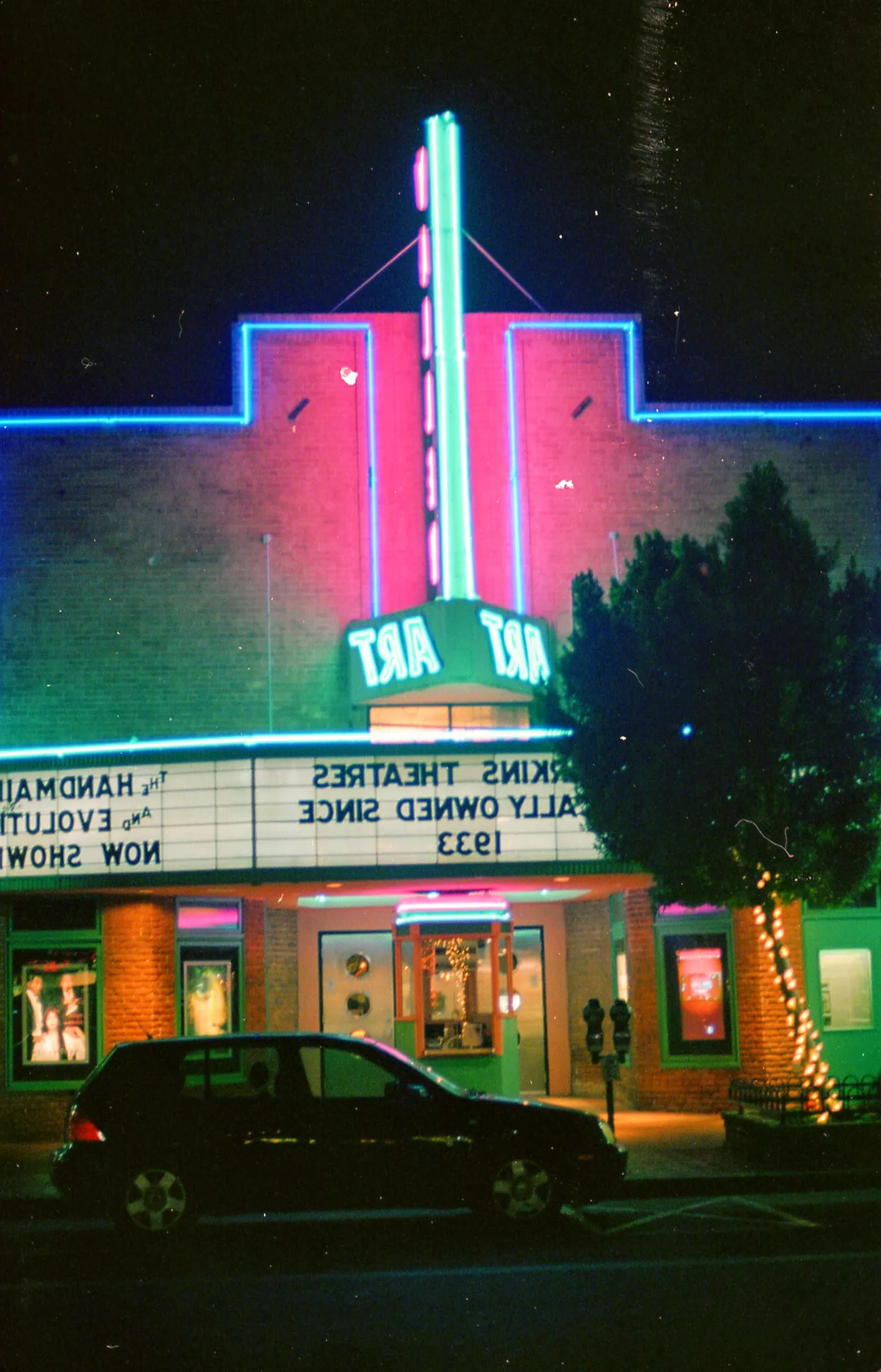 An illuminated Art Deco cinema facade photographed at night.