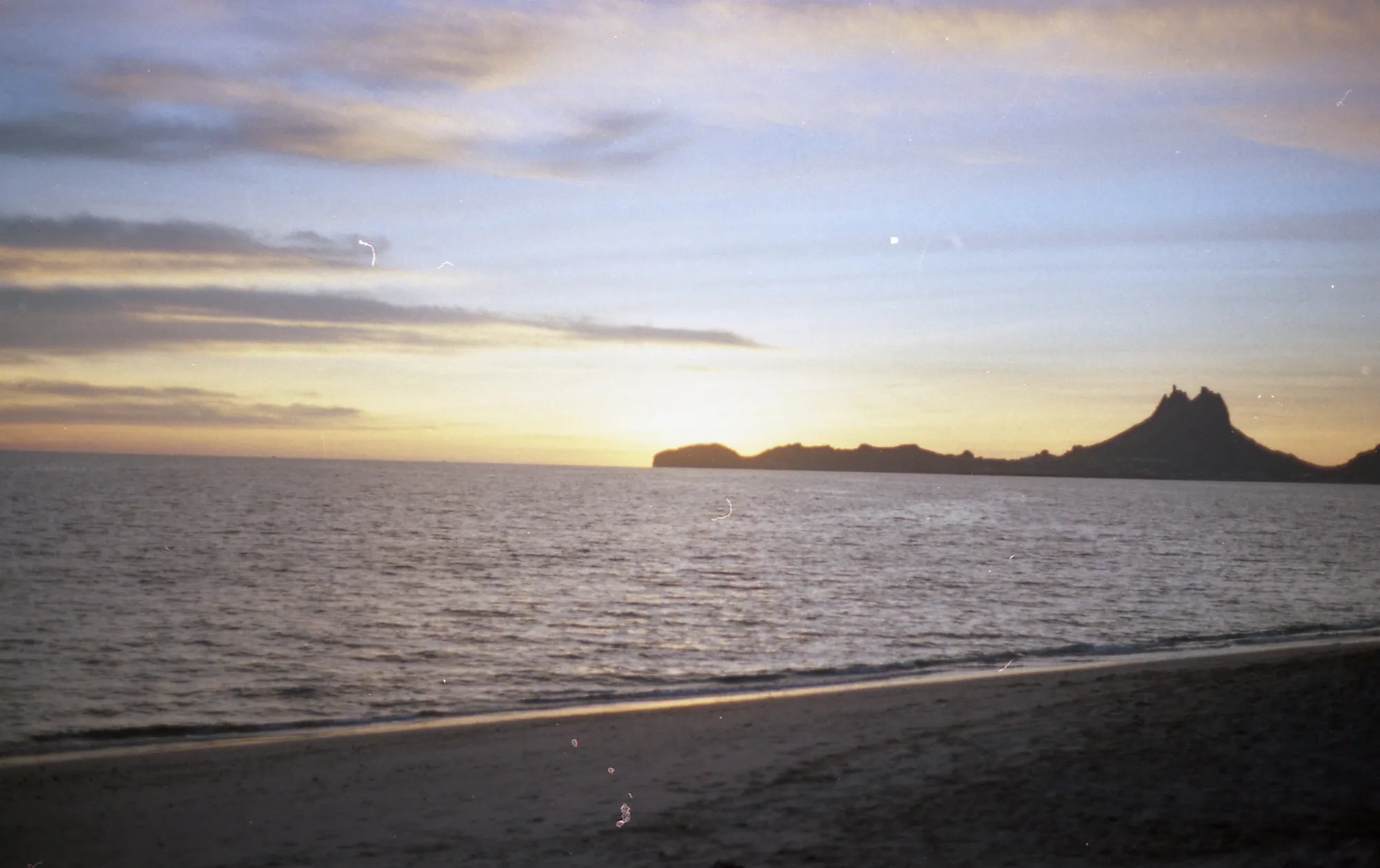 A dark coastline extending into a gold and blue sunset.