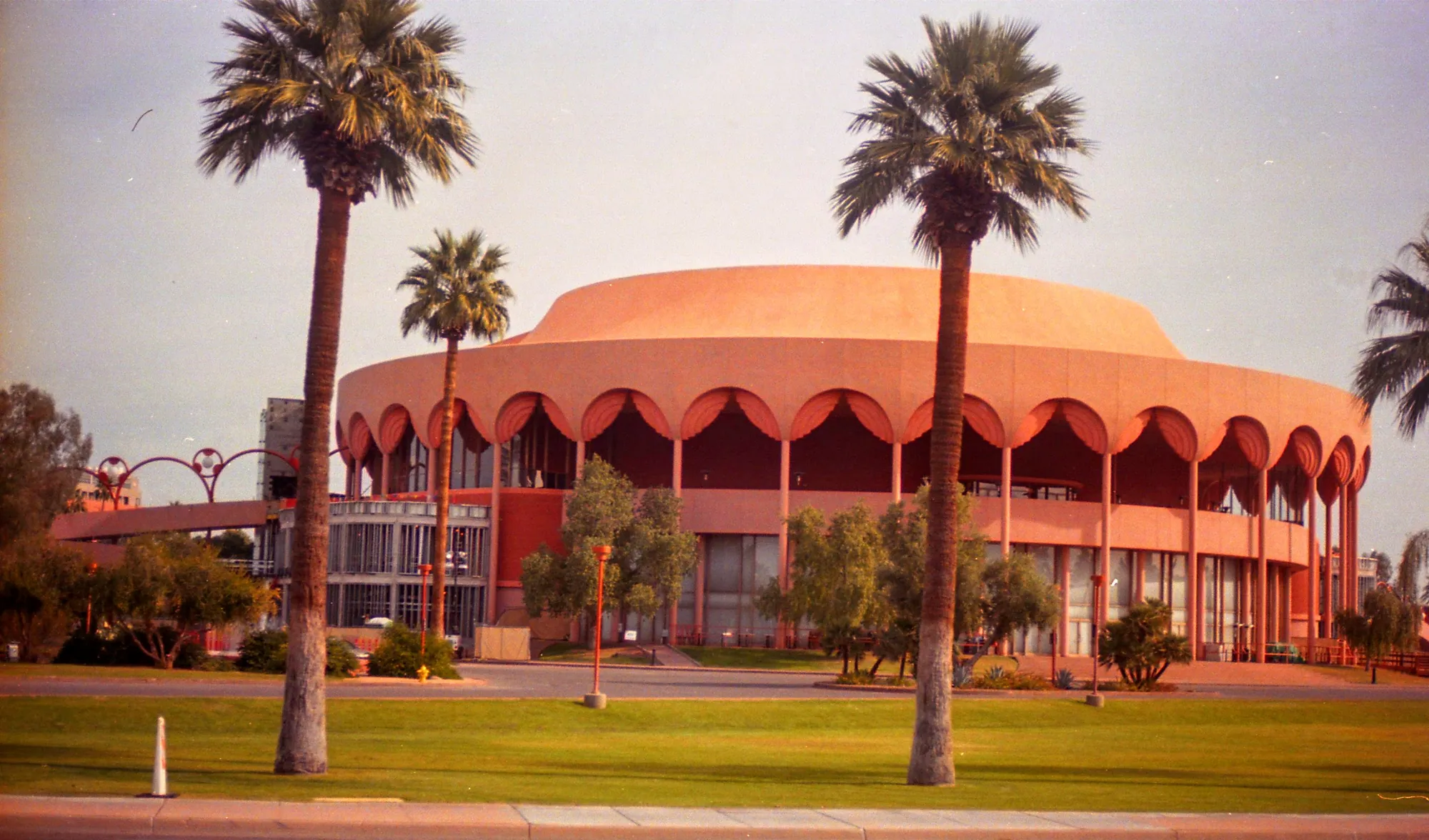 Coral-coloured architecture and palms in hard daylight.