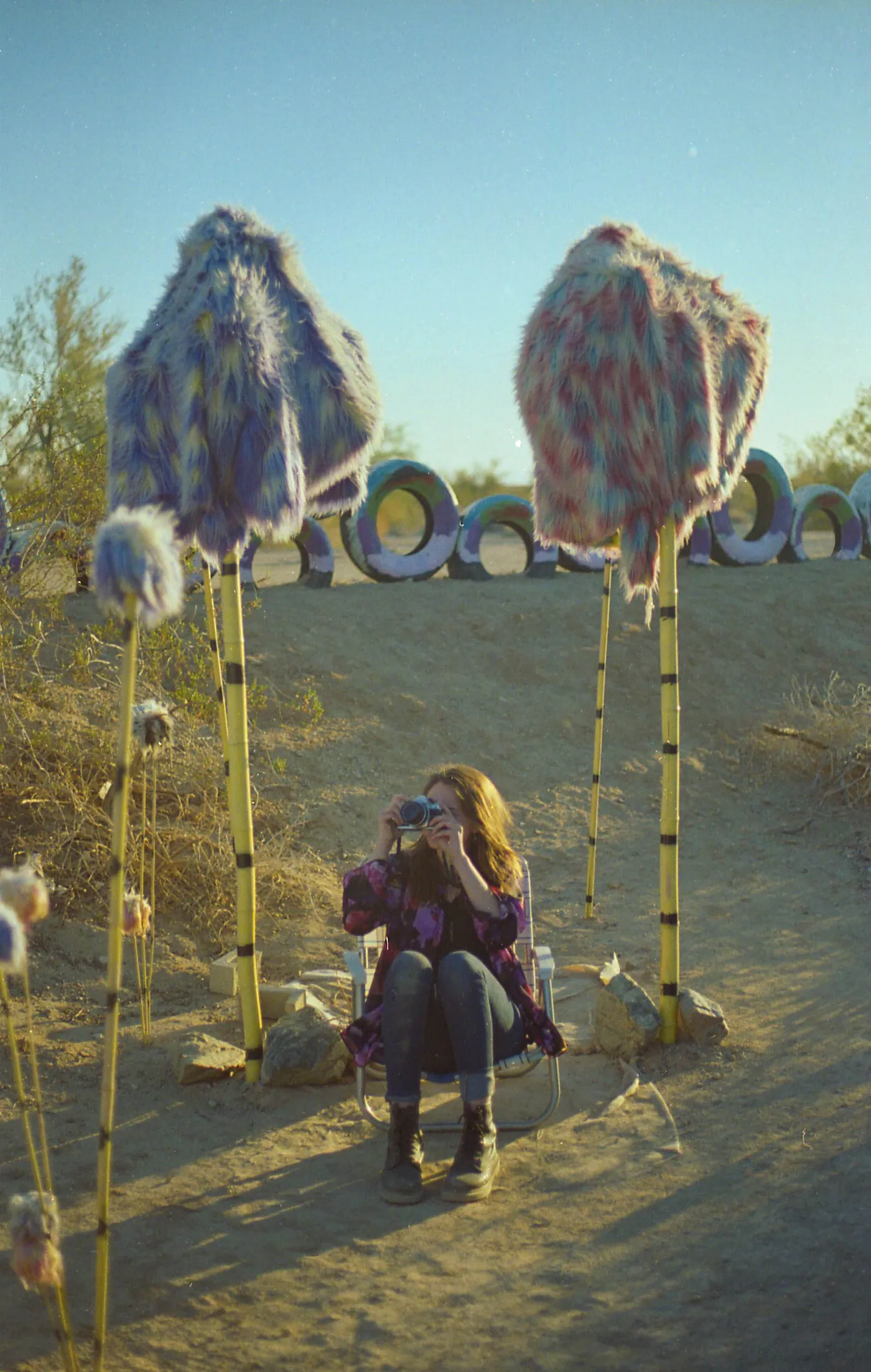 A photographer standing among tall handmade forms in a desert landscape.