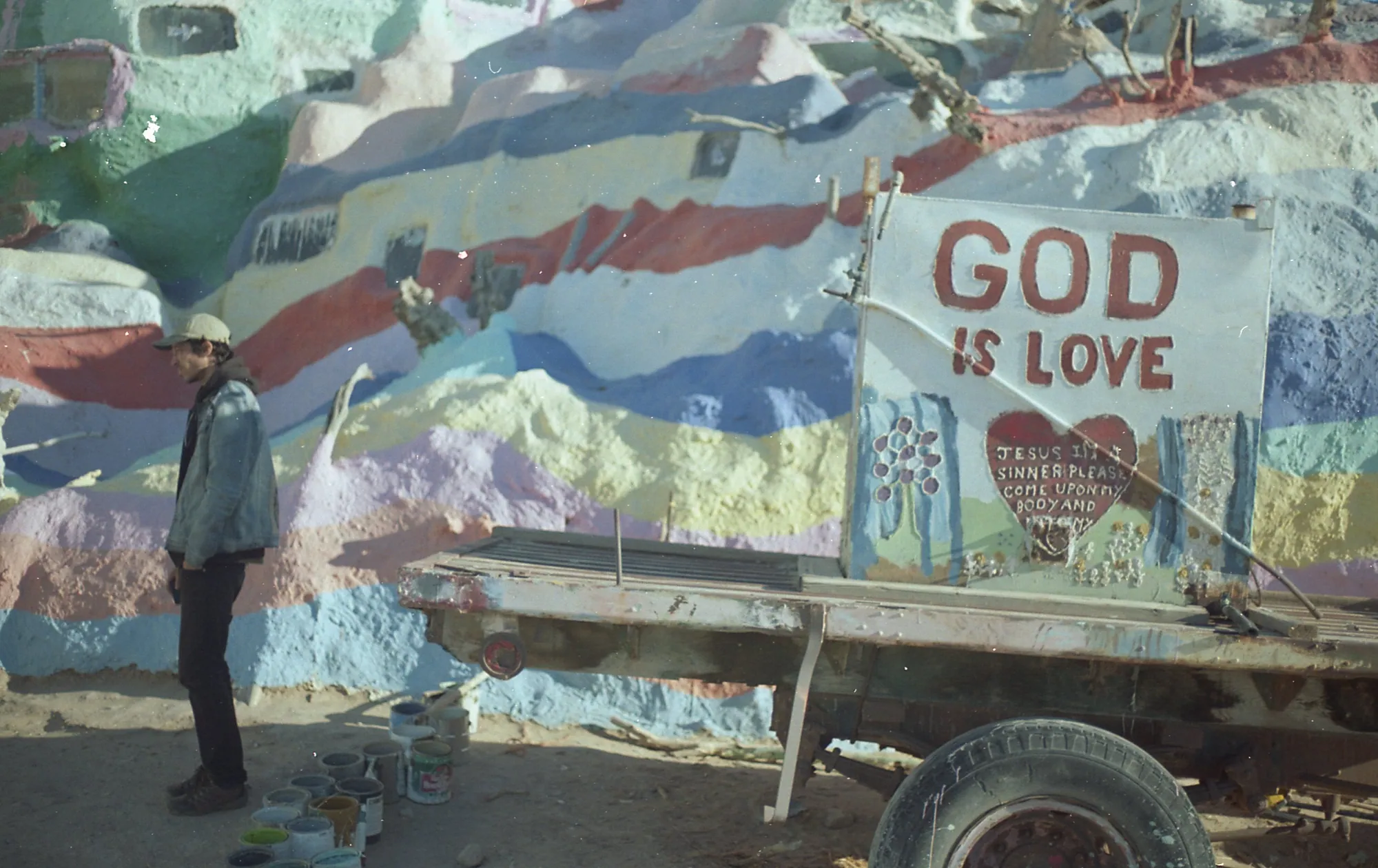 A person beside a painted trailer in the desert.