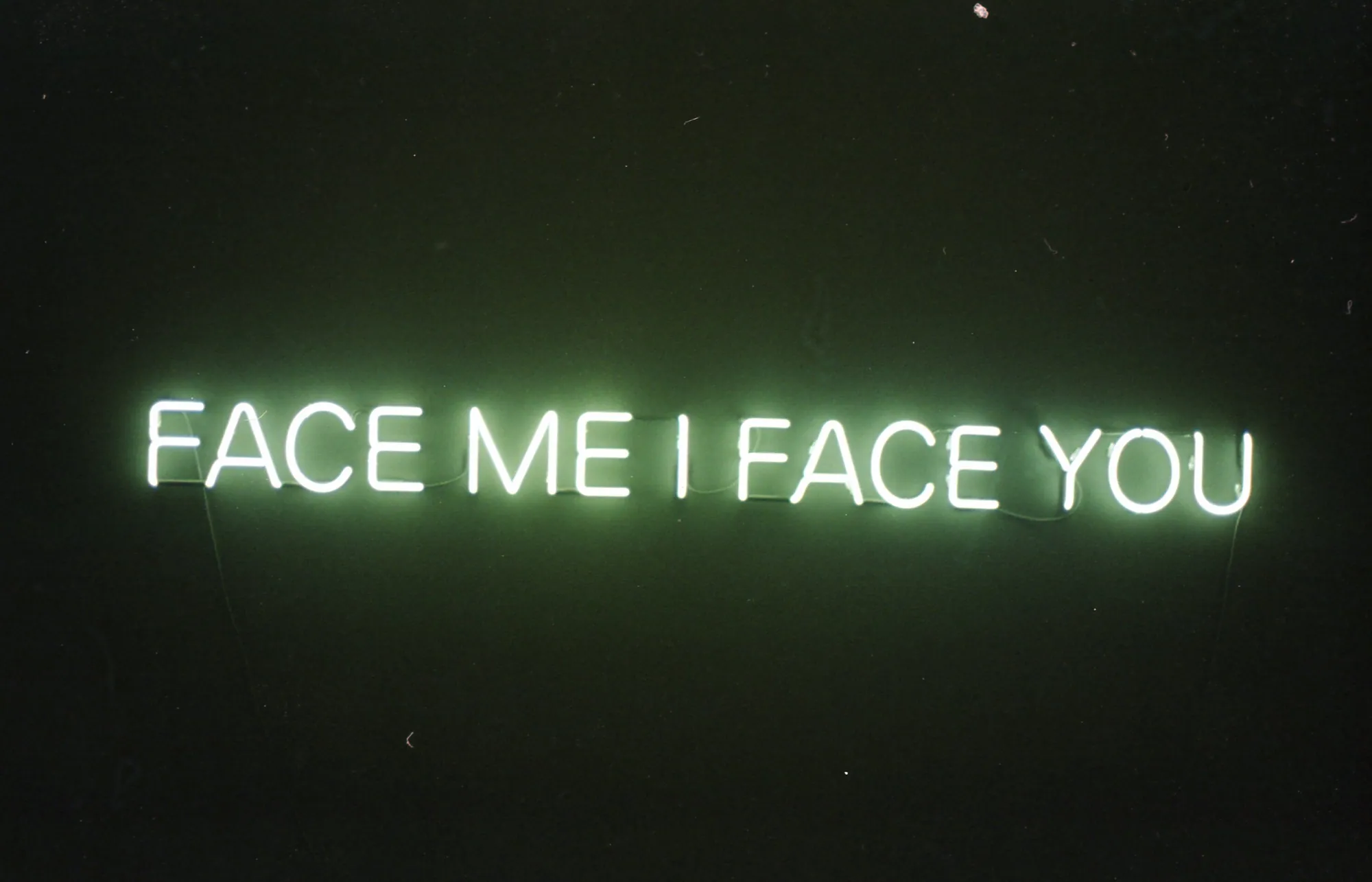 A red neon artwork glowing in a dark room.