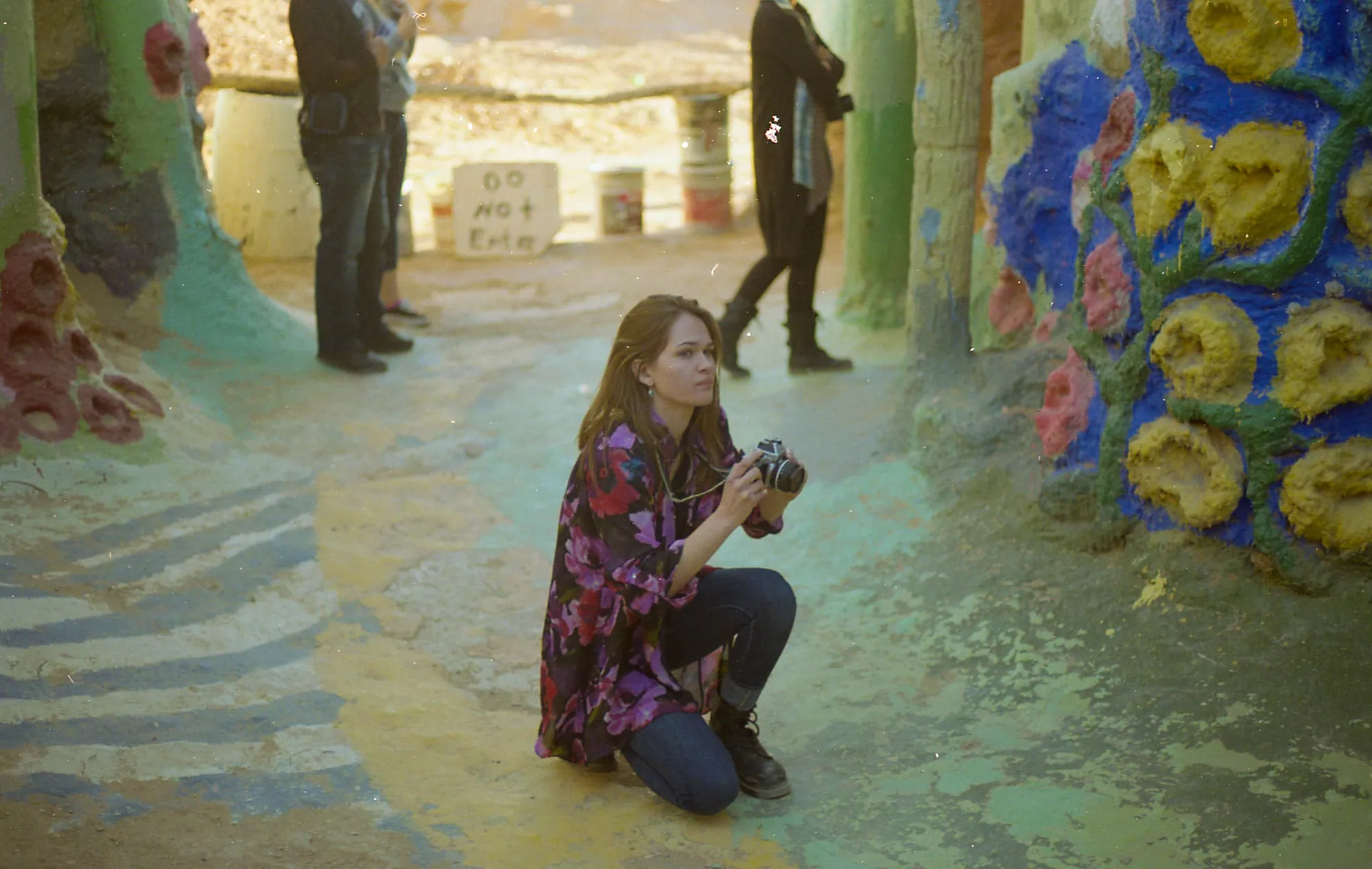 A photographer crouched inside a vividly painted folk-art grotto.