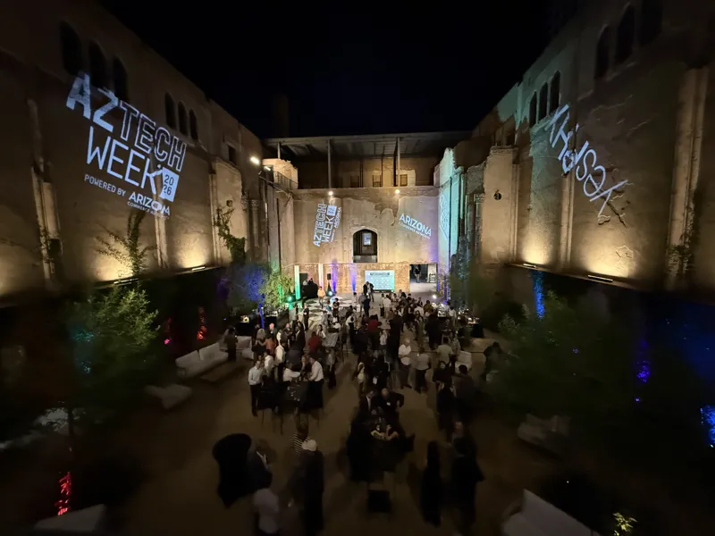 Guests mingling in an uplit courtyard at dusk