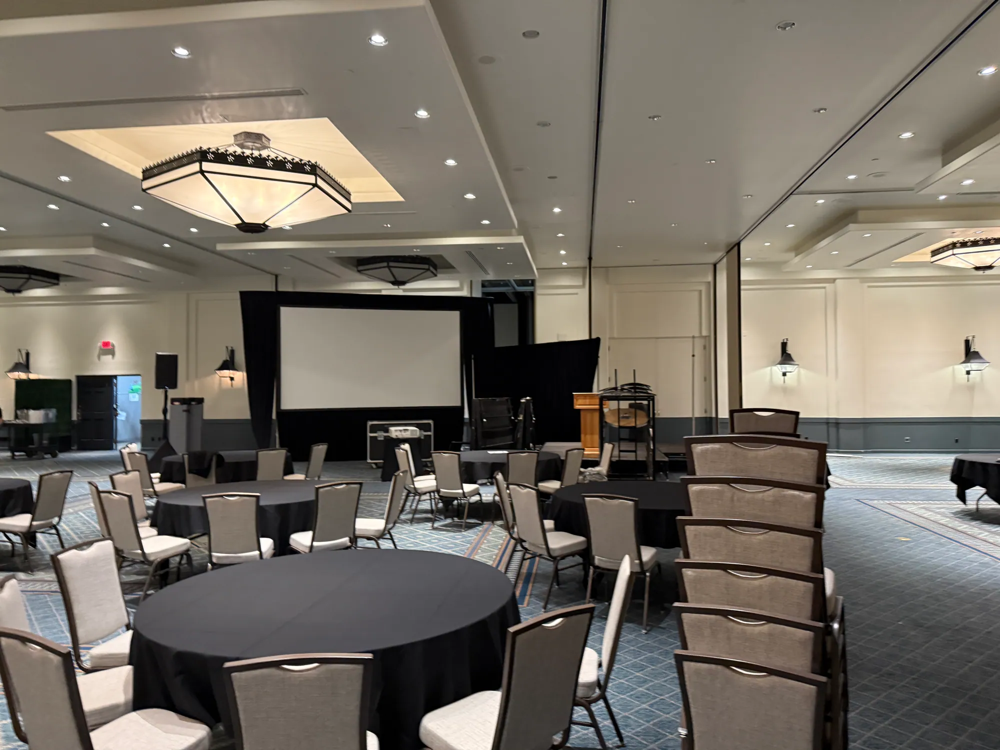 Rig, screen, stage, and control position in an event room before doors — the visible evidence that “we’ll figure it out” has become an actual plan.